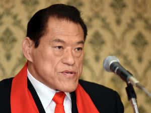 身穿西裝和紅色領帶的男子在正式活動中對著麥克風說話。 — 運動 壁紙