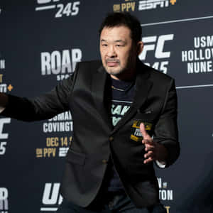 UFC拳手身穿黑色西裝外套和T恤在記者會上做手勢。 — 庫洛魔法使 壁紙