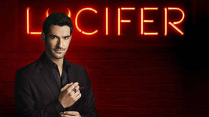 身穿黑色西裝的男子在磚牆上的紅色霓虹燈 Lucifer 標誌下拿著筆。 — 六人行 壁紙