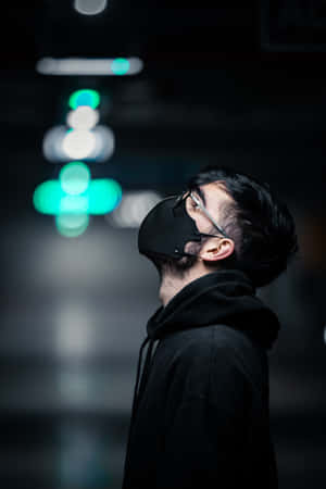 身穿黑色連帽衫和口罩的男子在黑暗隧道中仰望發光的綠色燈光。 — 駭客面具 壁紙