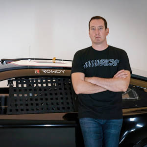 身穿黑色遙控車T恤的男子站在帶有「ROWDY」標誌的黑色賽車旁。 — 運動 壁紙