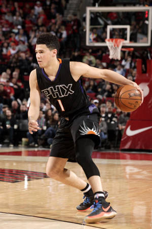籃球運動員在比賽中運球，面前是歡呼的人群。 — Devin Booker 壁紙