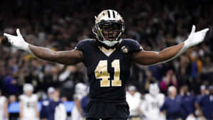 足球員41號在夜間球場張開雙臂慶祝勝利。 — Alvin Kamara 壁紙