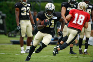 比賽中帶球奔跑的足球運動員 — Alvin Kamara 壁紙