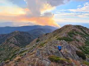 遠足者在熾熱夕陽與戲劇性雲彩中的山脊上 — 登山 壁紙