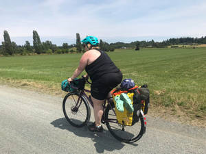 騎自行車者在鄉村碎石路上騎著載滿行李的旅行自行車穿過綠色田野 — 登山車 壁紙