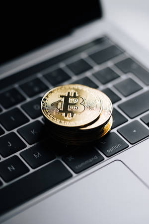 筆記型電腦鍵盤上的一堆金色比特幣硬幣