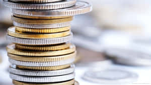 高聳的金幣和銀幣堆，背景有模糊的硬幣。 — 金色動態 壁紙