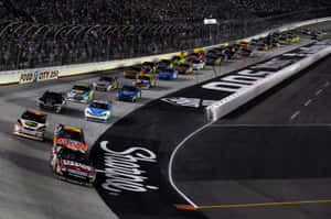 夜間NASCAR比賽，賽車在明亮燈光下於賽道上飛馳。 — 美國 壁紙