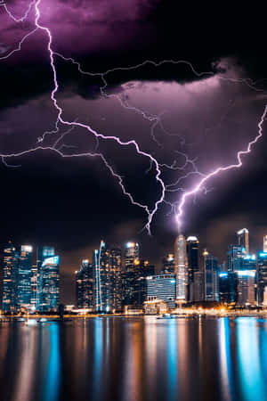 紫色閃電劃過發光的城市天際線，夜晚倒映在水中。 — 閃電 壁紙