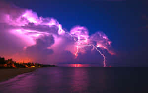 夜晚黑暗的海洋上空，紫色閃電在海灘附近閃現。 — 紫色夜空 壁紙