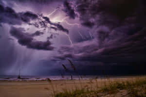 紫色風暴雲伴隨閃電，海灘上有一艘帆船。 — 閃電 壁紙