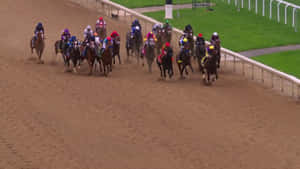 騎師在賽馬期間於泥地賽道上策馬競賽。 — 賽馬 壁紙