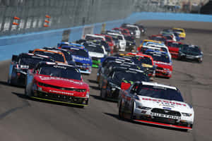 NASCAR賽車在日落時分於賽道上飛馳。 — 美國 壁紙