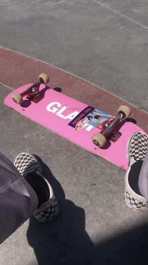 帶有「GLAT」標誌的粉紅色滑板和混凝土路面上的格紋鞋。 — 滑板 GIF 壁紙