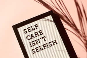 字母板顯示 self care isn't selfish，粉紅牆上有棕櫚葉影子 — 高清 壁紙