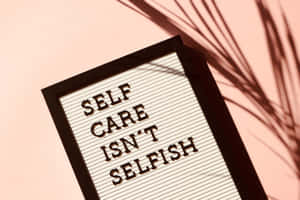 字母板寫著 self care isn't selfish，粉紅牆上有棕櫚葉影子。 — MacBook Pro 16 壁紙