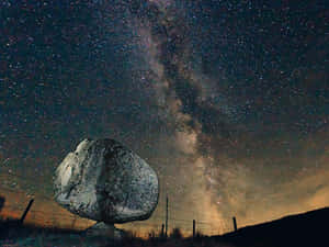 星空夜空下的一塊大岩石，銀河可見。 — 銀河月亮 壁紙