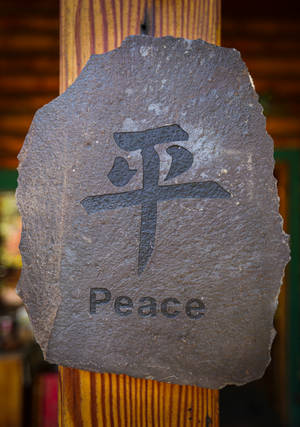 一塊石牌，上面刻有漢字「平和」和英文單詞「peace」。 — OnePlus Pad 3 壁紙