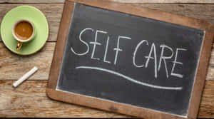 黑板寫著self care，旁邊有一杯咖啡在木上。 — 16:9 壁紙