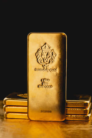 一堆金條，其中一塊直立，帶有獅子徽章和雕刻細節。 — 金色質感 壁紙