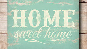 風化的青綠色木牌，寫著「HOME sweet home」，掛在質樸的牆上。 — 甜蜜的家 壁紙
