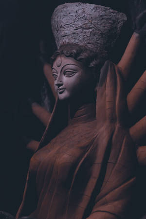在昏暗光線中，一尊寧靜的石像，神祇戴著紋理王冠，身披垂墜長袍。 — 雕塑 壁紙