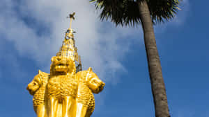 金色三頭獅子雕像在藍天下棕櫚樹旁 — 藍天 壁紙