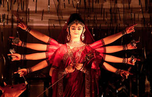 印度教女神杜爾迦的紅金色雕像，多臂手持武器。 — Maa Durga 壁紙