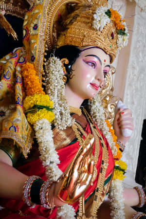 寺廟中裝飾著紅白花朵的金色神像。 — Maa Durga 壁紙