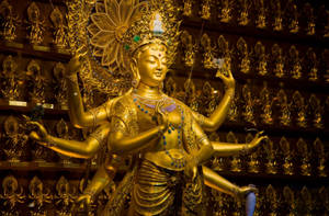 金色多臂佛像被寺廟內較小的金色佛像環繞。 — Maa Durga 壁紙