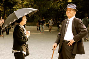 一對年長夫婦在日落時分的公園裡交談。 — 日式 壁紙