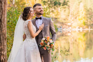 幸福的新郎新娘在秋葉環繞的湖邊擺姿勢。 — 婚禮 壁紙