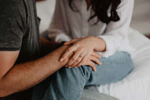 一對情侶在床上牽手，可見訂婚戒指。 — 情侶擁抱 壁紙