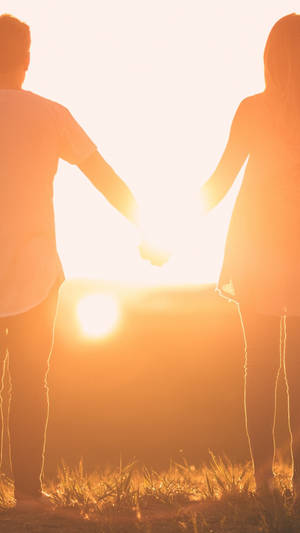 情侶在夕陽下牽手剪影（草地上） — 日落 壁紙