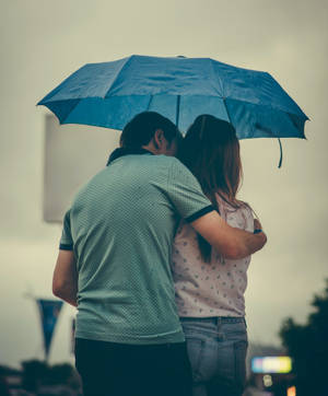 一對情侶在黃昏的城市環境中共享雨傘。 — 情侶擁抱 壁紙