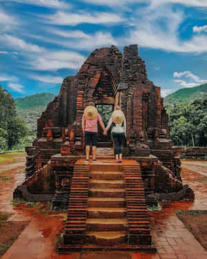 兩人在被山脈環繞的歷史寺廟遺址上手牽手。 — 越南 壁紙