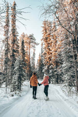 兩人在冬日裡手牽手走過白雪覆蓋的森林。 — 冬季風景 壁紙