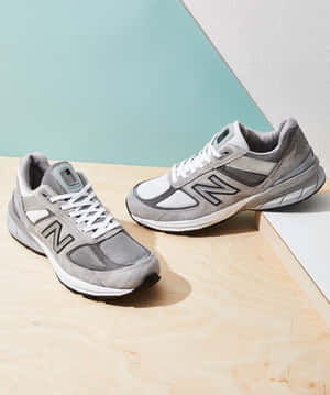 灰色New Balance運動鞋放在木質表面上，背景為藍綠色和白色。 — New Balance 壁紙