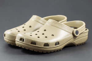 灰色背景上的米色木屐，配有可調節搭帶。 — Crocs 壁紙