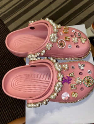 粉紅色Crocs木屐覆蓋著珍珠、水鑽和設計師標誌。 — Crocs 壁紙