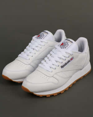 灰色背景上的白色Reebok Classic運動鞋搭配橡膠鞋底。 — 銳步 壁紙