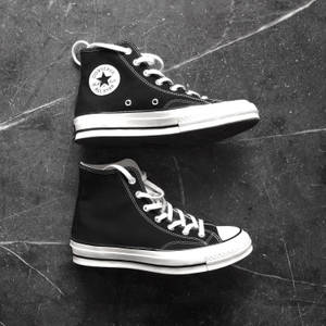 黑色Converse運動鞋，白色鞋帶，放在有刮痕的灰色混凝土地板上。 — 黑色天使翅膀 壁紙