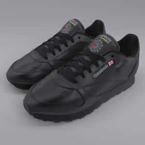 黑色Reebok Classic運動鞋，帶有紅色和灰色細節，背景為灰色。 — 銳步 壁紙