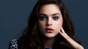 一位藍眼睛、深色頭髮的年輕女性，將手放在臉旁擺姿勢。 — 女演員 壁紙