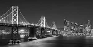 夜間城市景觀，燈光璀璨的海灣大橋和摩天大樓倒映在水中。 — 舊金山 壁紙