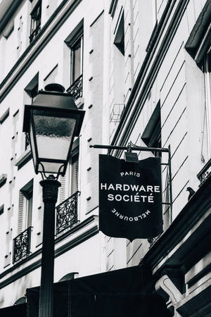 黑白街景，歐洲建築上有復古燈和Hardware Société標誌。 — 香奈兒 壁紙