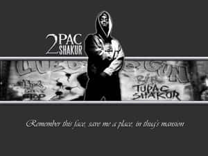 Tupac Shakur 穿著連帽衫，站在塗鴉牆前，牆上有紀念標籤。 — 嘻哈 壁紙