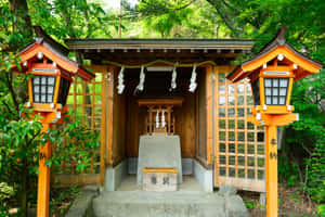 一座木製日本神社，周圍環繞著綠樹，兩側有橙色燈籠。 — 日式自然壁紙