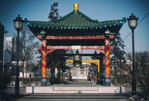 白雪覆蓋的城市公園中的傳統亭子，有龍柱和綠色屋頂。 — 桌面 壁紙